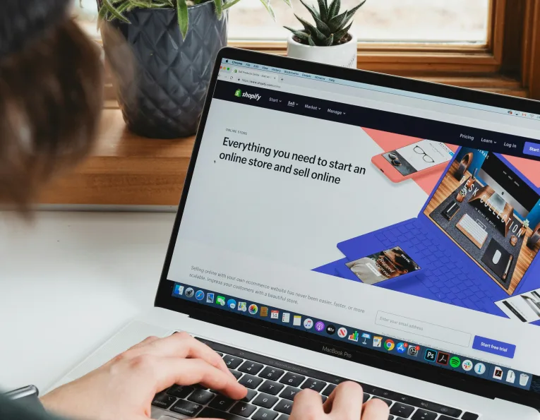 Mains sur un ordinateur portable affichant la page d’accueil de Shopify